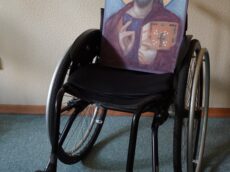 zdjęcie: wózek inwalidzki na którym znajduje się ikona Jezusa Pantokratora.